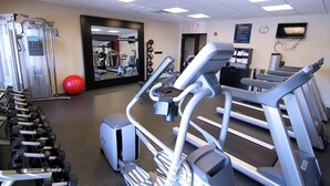 Et fitnesscenter med løbebånd, håndvægte og træningsmaskiner.