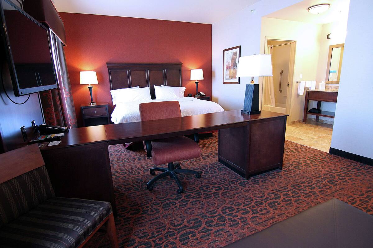 Une chambre d’hôtel équipée d’un lit, d’un bureau, de chaises et d’une télévision.