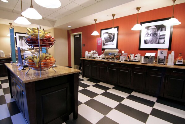 Un coin cuisine avec un carrelage à motifs, un panier de fruits sur le comptoir et un espace dédié au café.
