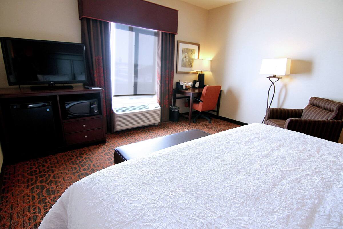 Une chambre d’hôtel avec un grand lit, une télévision, un bureau et une chaise.
