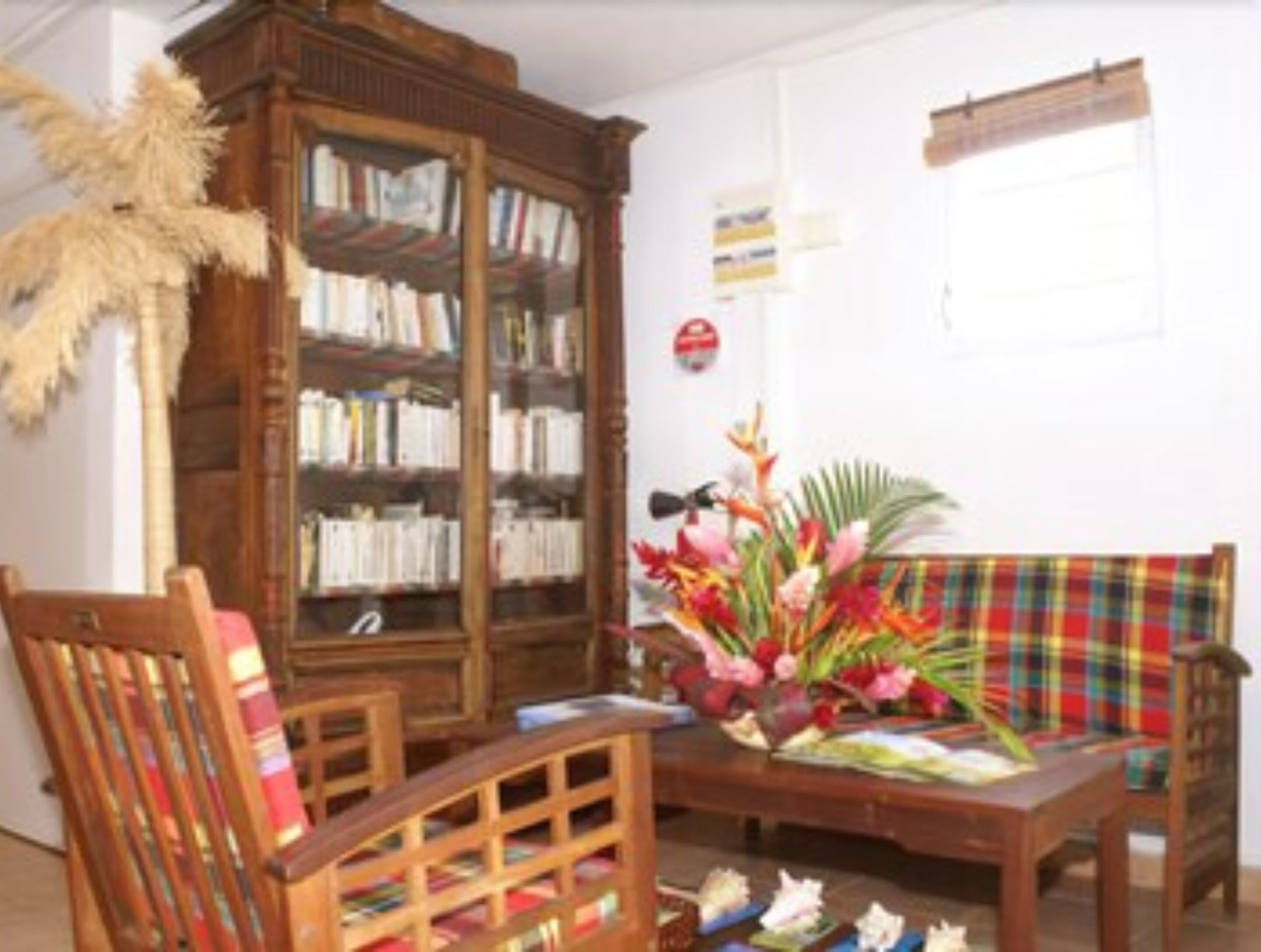 A room with a wooden bookshelf, a plaid sofa, a wooden table, and a decorative plant.