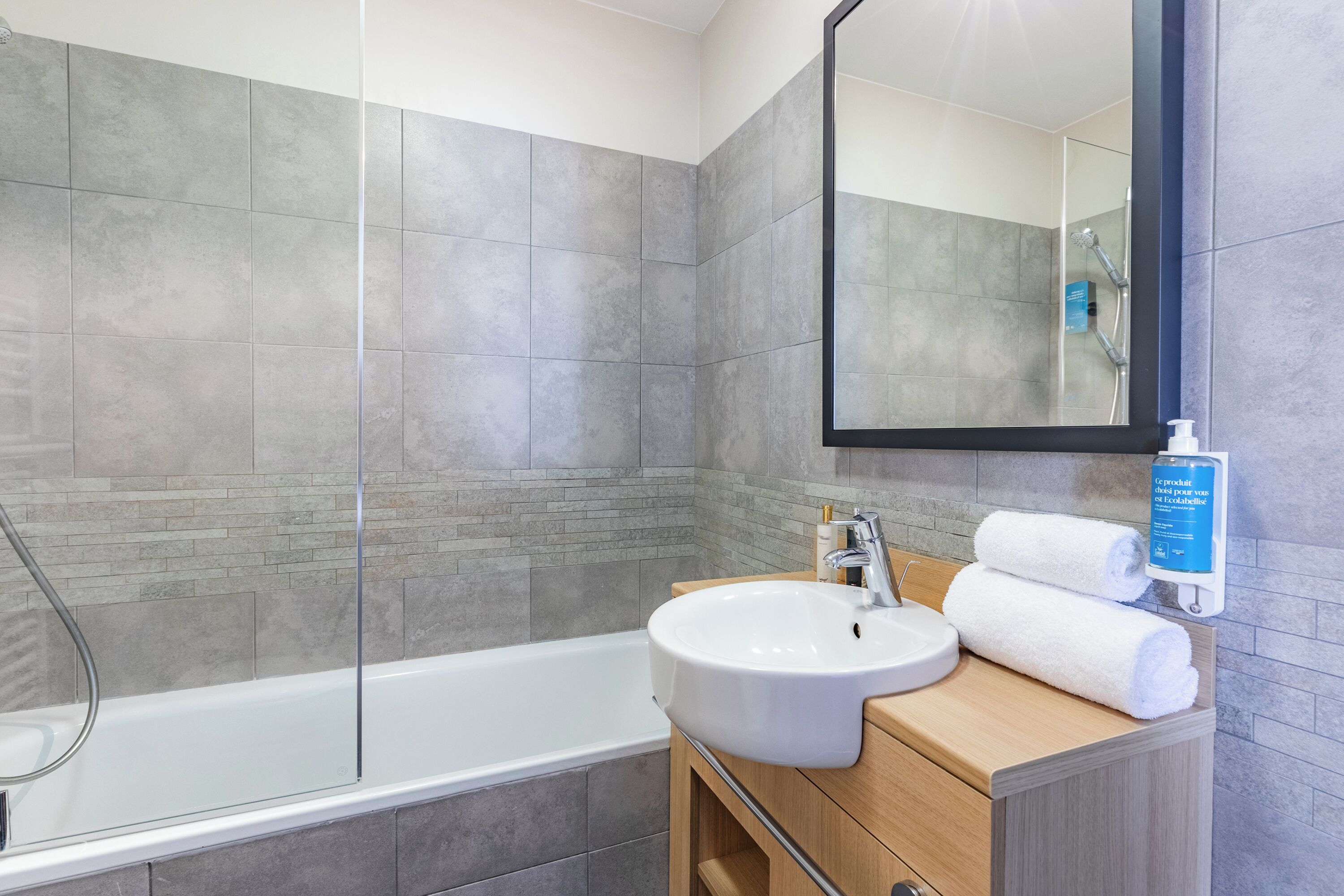 Un baño moderno con bañera, lavamanos y espejo.