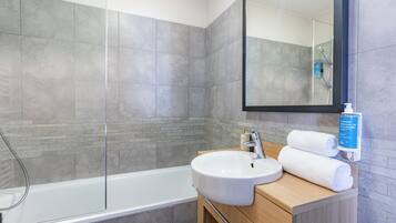 Un baño moderno con bañera, lavamanos y espejo.