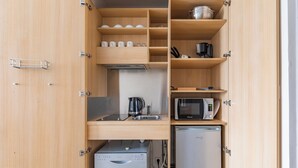 Cocina compacta con microondas, cafetera y refrigerador pequeño.