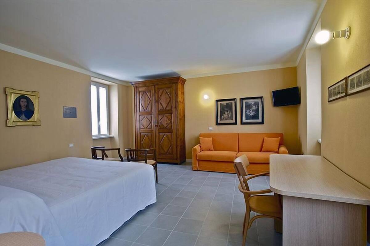 A room with a bed, a sofa, a TV, and a wooden cabinet.
