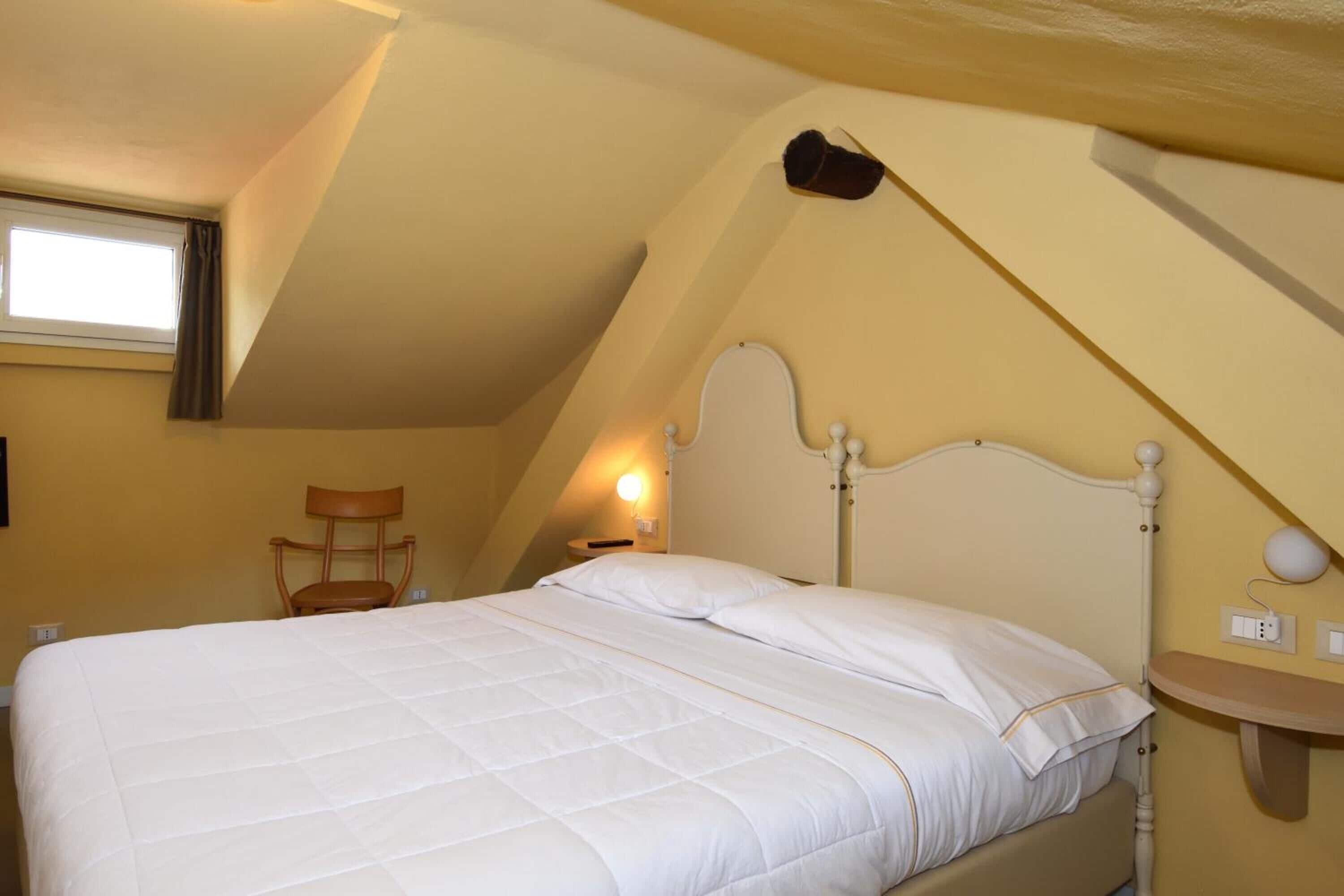 Une chambre à coucher comprenant un lit, une chaise, une table de chevet et une lampe fixée au mur.