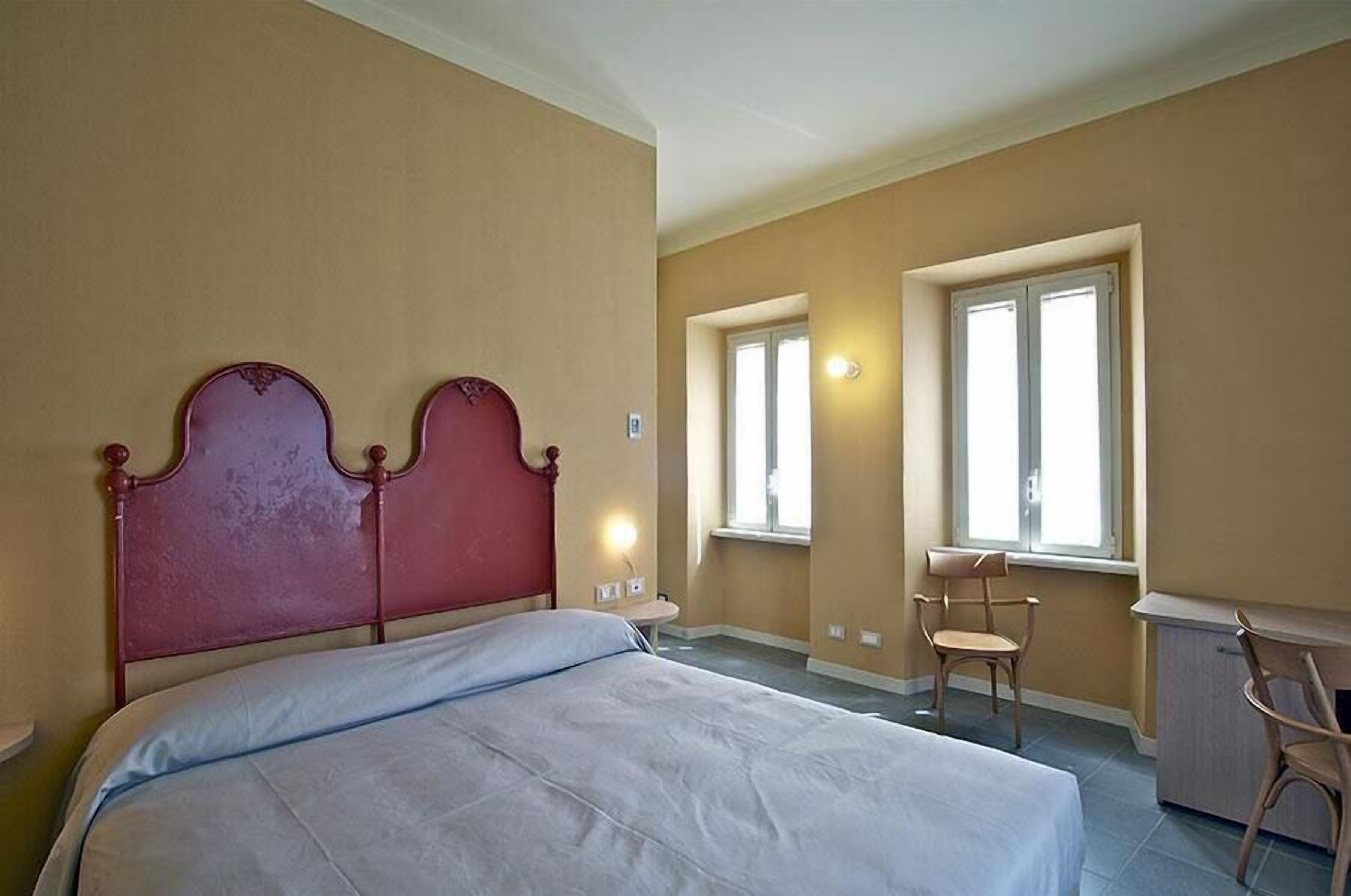 A bedroom with a large bed, two bedside tables, a desk, and two chairs.
