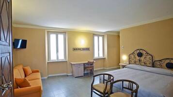 Una habitación de hotel con cama, escritorio, silla y sofá.