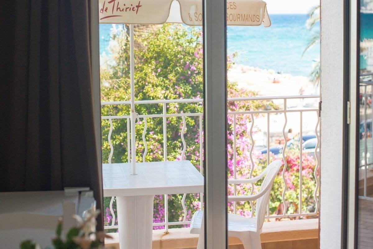 Une chambre avec un balcon, une table et un parasol.