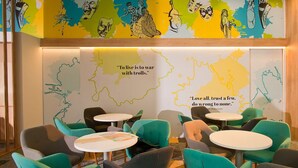 A modern lounge area with teal and gray chairs and small round tables, featuring a map and quotes on the wall. - B&B HOTEL Maribor UNI Hostel (Maribor)