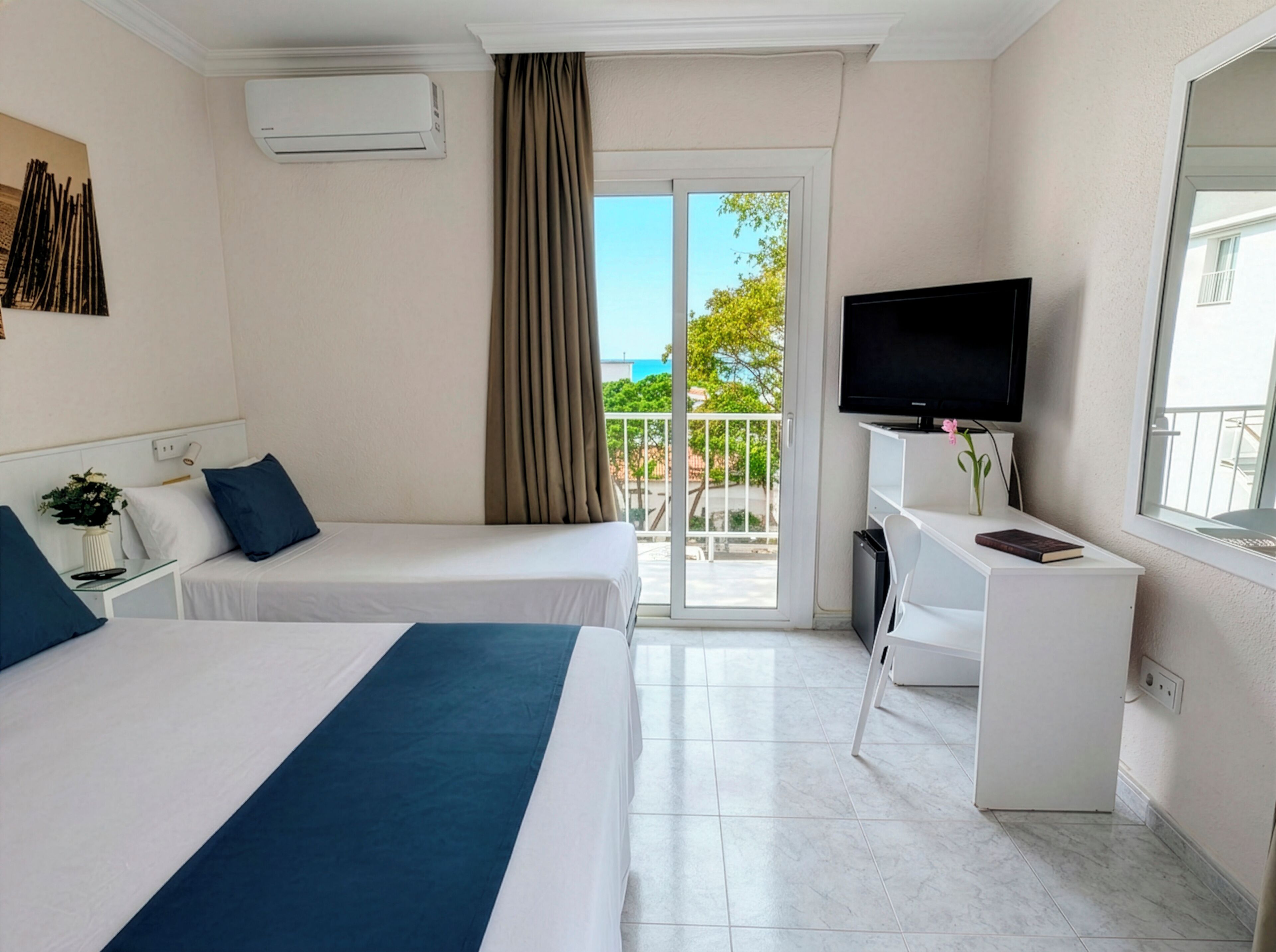Une chambre d’hôtel avec deux lits, une télévision, un bureau et un balcon avec vue.
