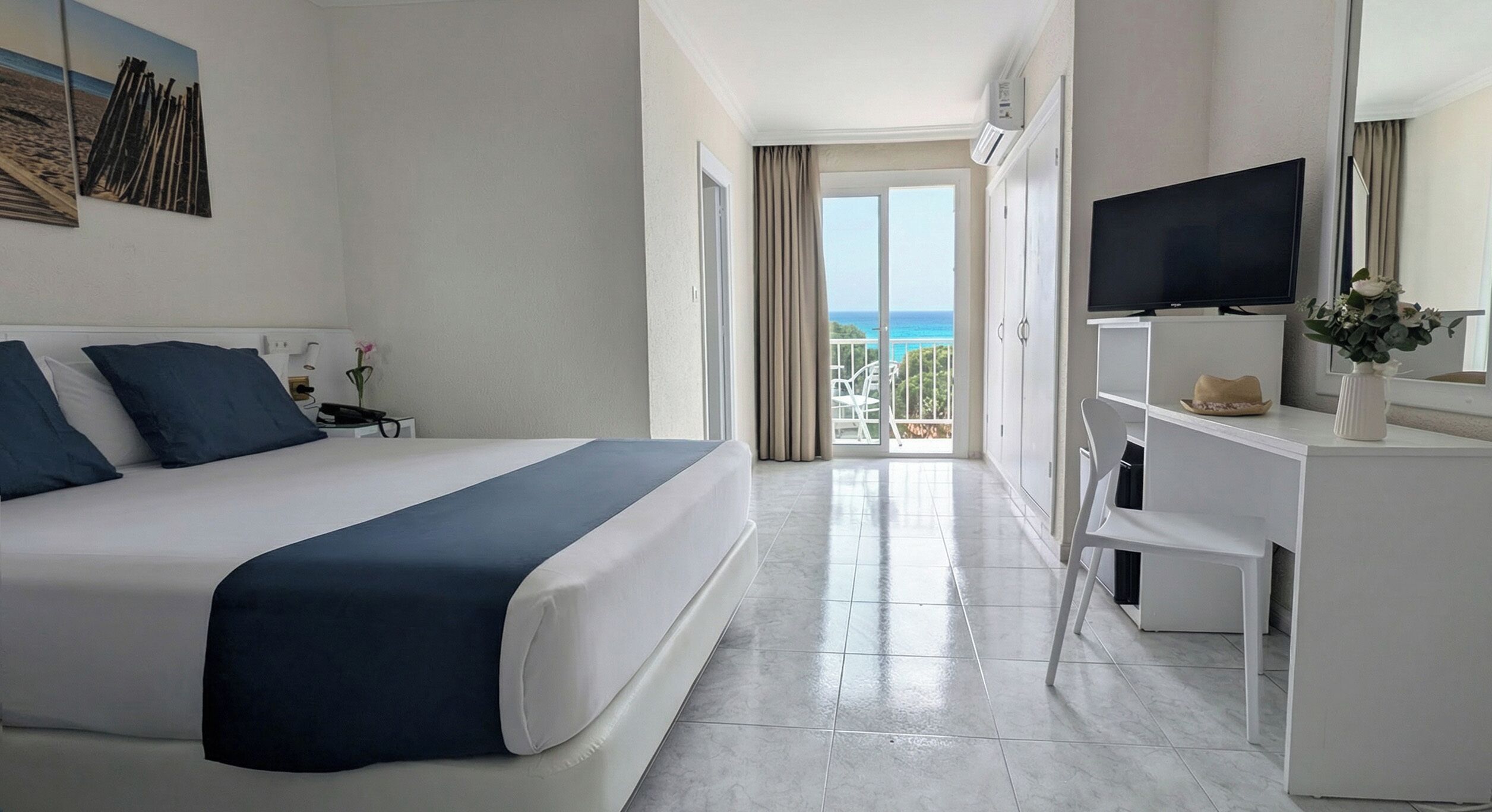 Une chambre d’hôtel avec un lit, une télévision, un bureau et une vue sur l’océan.