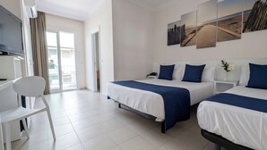Habitación de hotel con dos camas, un escritorio, una silla y un televisor.