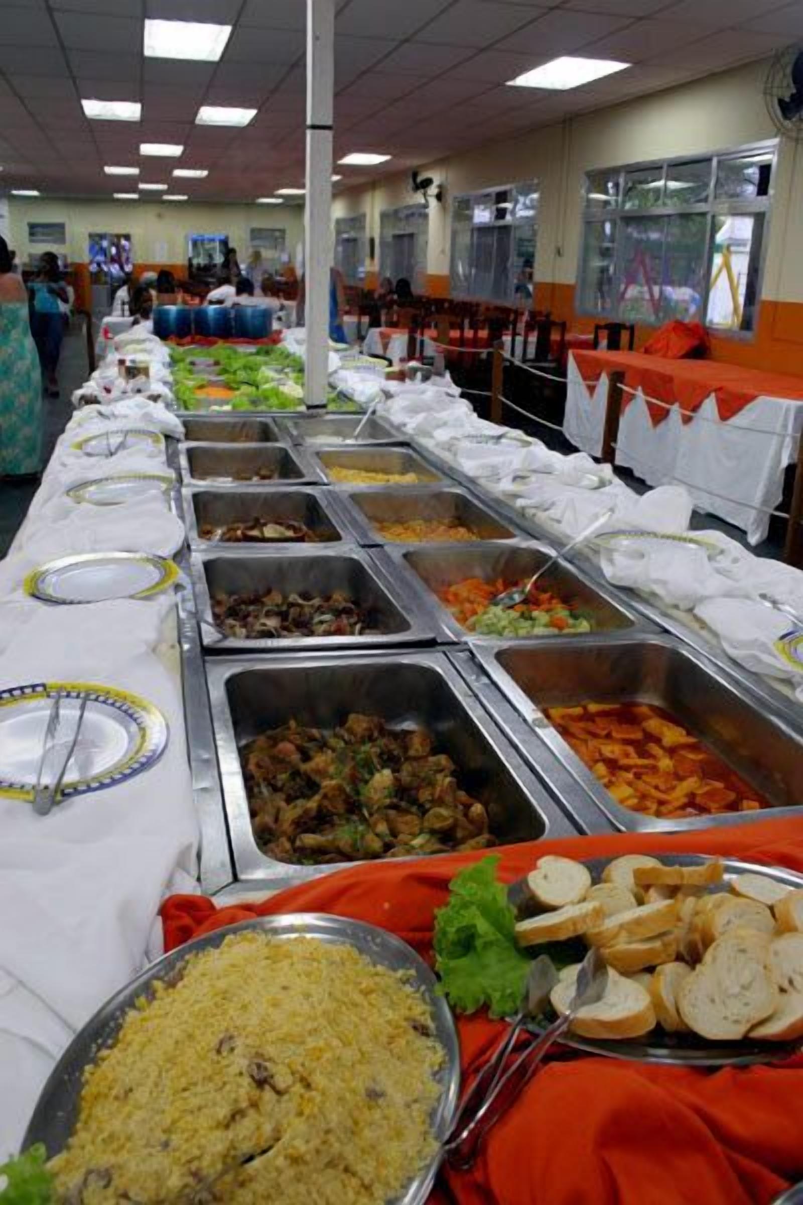 Un bufé con diversas opciones de comida, como arroz, verduras y carnes, dispuestas en bandejas de acero inoxidable.