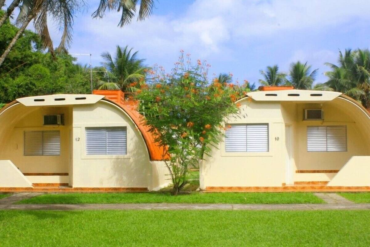 Two dome-shaped structures with windows and a small tree in between.