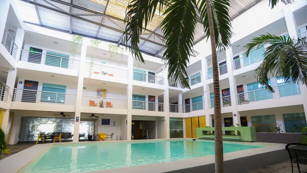 Un área de piscina interior de varios niveles con piscina central, múltiples balcones y plantas de interior.