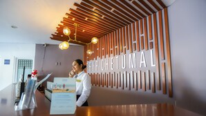 Un área de recepción de diseño moderno, con techo de listones de madera y un letrero montado en la pared.