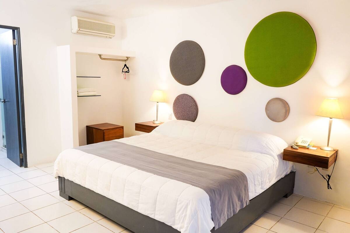 A modern bedroom with a large bed, bedside lamps, and wall-mounted decor.