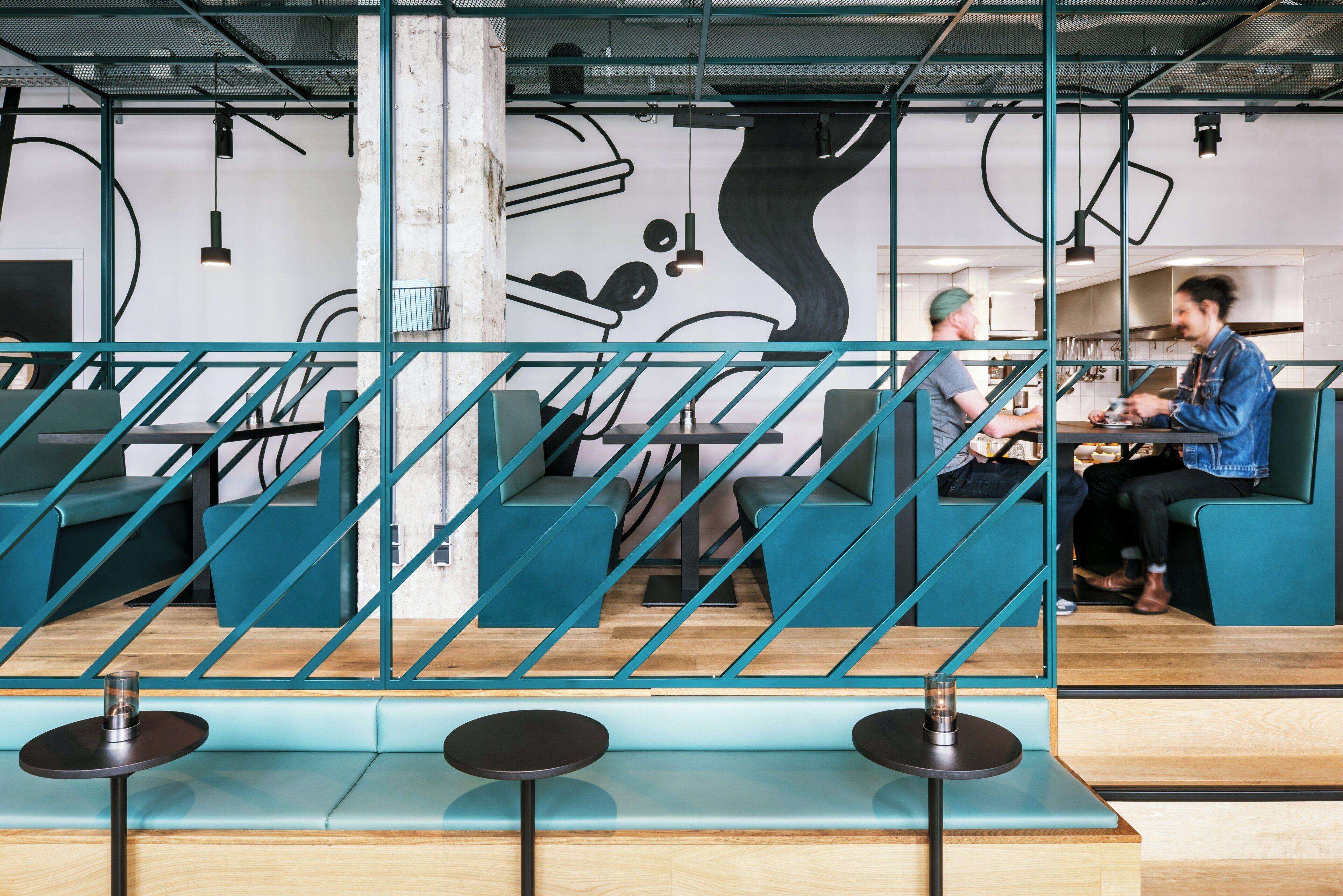 Un intérieur moderne avec des sièges de couleur turquoise, un escalier et une fresque murale.