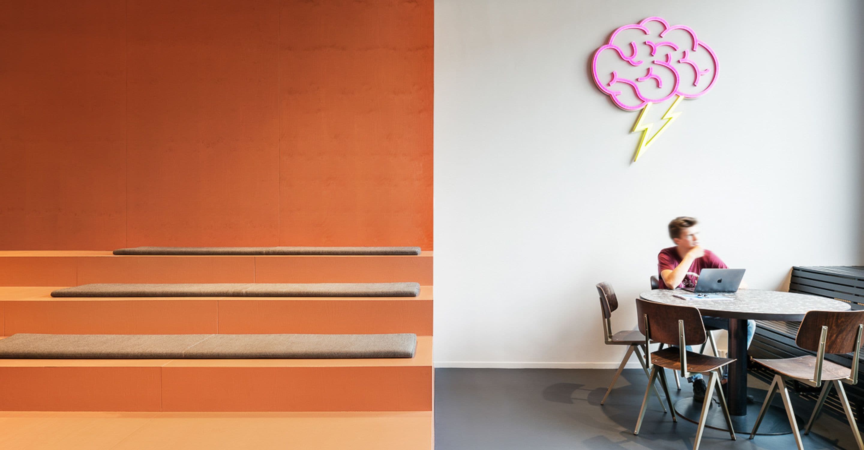 Un interior moderno con una zona de estar que incluye bancos y una mesa redonda con sillas.