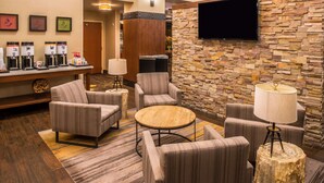 A lobby with seating, a coffee station, a TV, and a stone wall. - Hampton Inn & Suites Boulder-North (Boulder)