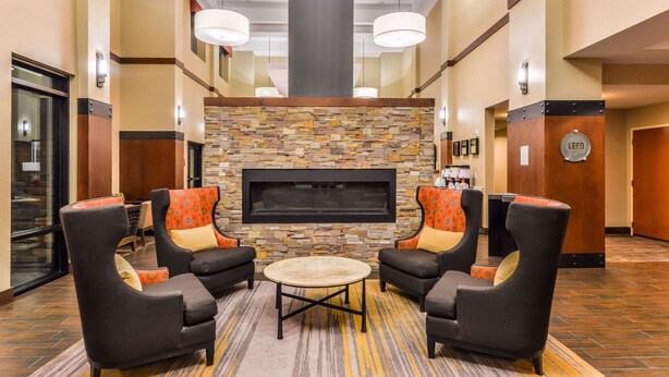 A lobby with a stone fireplace, two armchairs, a small round table, and a reception desk. - Hampton Inn & Suites Boulder-North (Boulder)