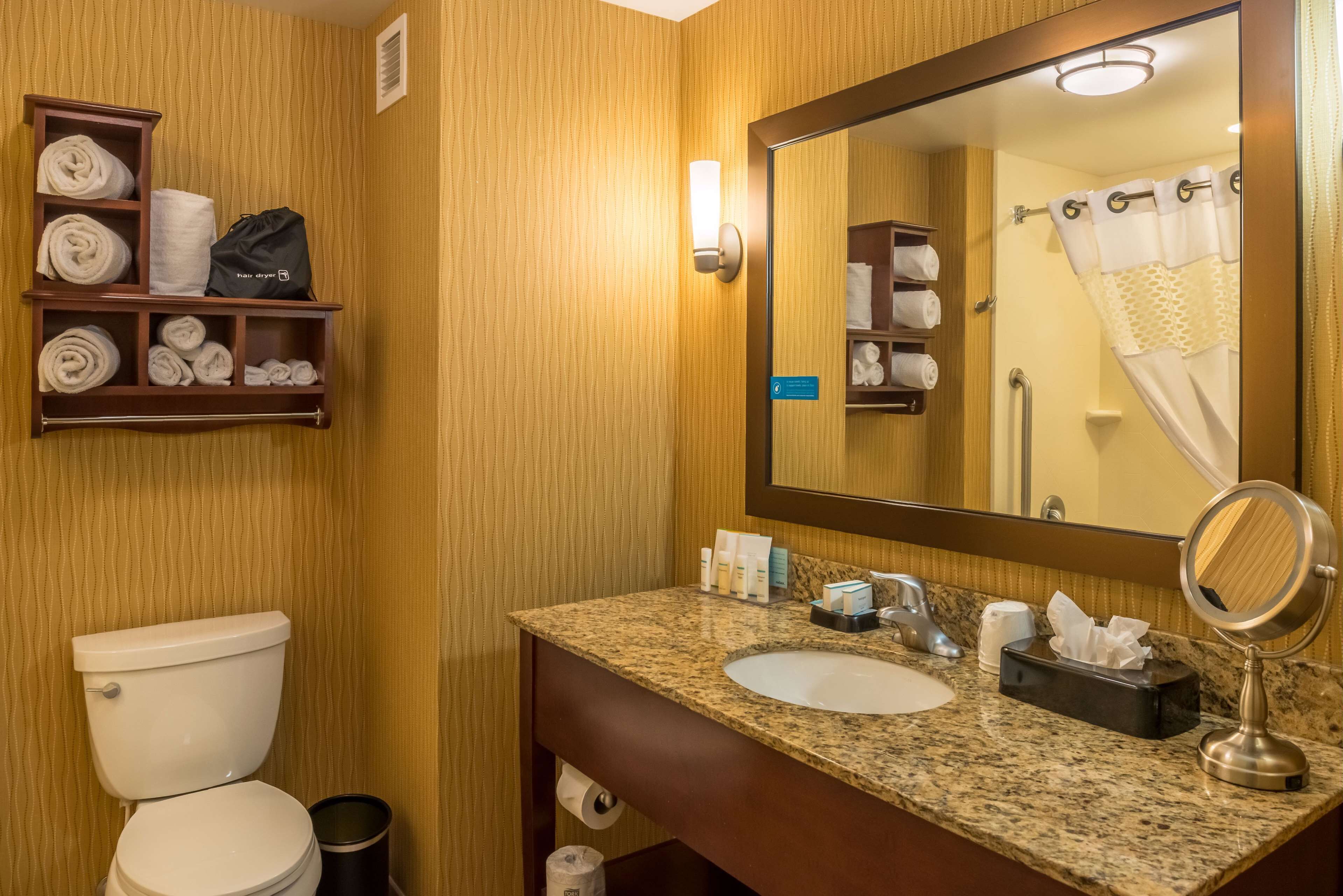 A bathroom with a toilet, sink, and towel storage.