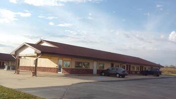 A motel with a single-story structure, a covered parking area, and a car parked in front.