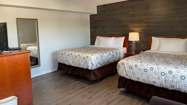 Une chambre d’hôtel avec deux lits, un bureau, un miroir et un plancher en bois.