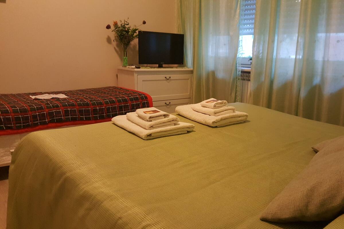 A hotel room with two beds, a television, and a window with curtains.