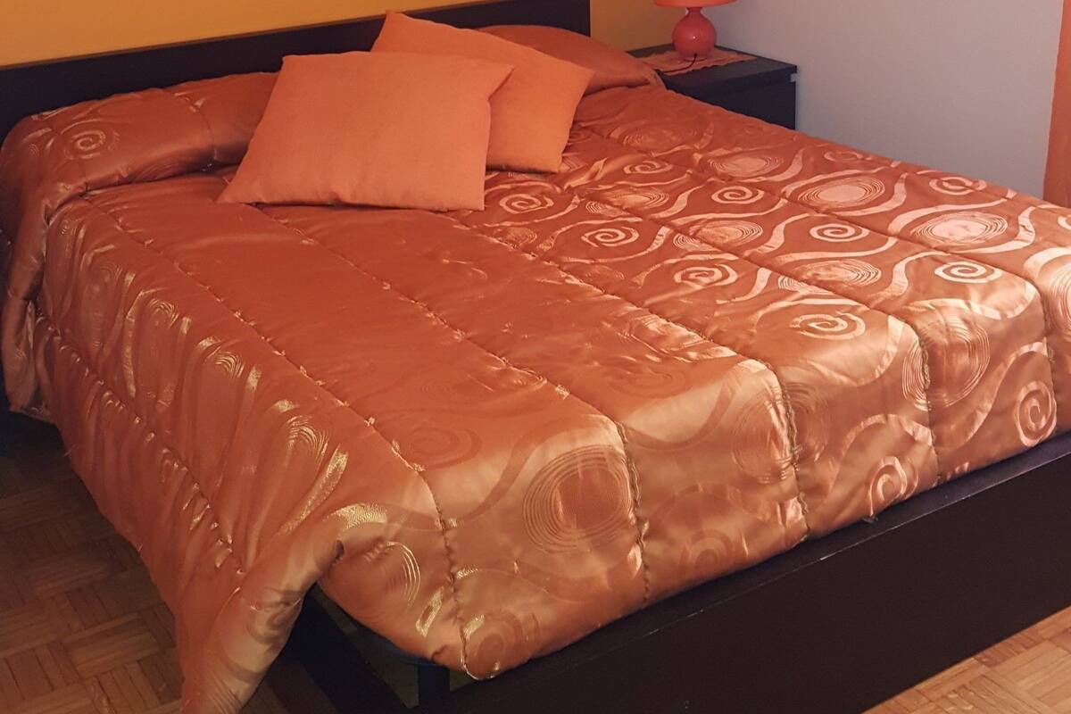 A bedroom with a bed, a nightstand, a lamp, and two paintings on the wall.