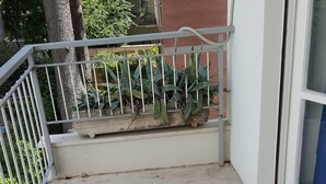 A balcony with a white railing, a concrete floor, and potted plants. - Domina Romae B&B (Rome)