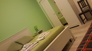 A room with a bed, a nightstand, a green wall, and a door leading to another room. - Domina Romae B&B (Rome)
