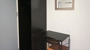 Et lille rum med et sort klædeskab, et lille træbord og et spejl på væggen.