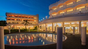 Un hotel con varios balcones, piscina y un área exterior bien iluminada.