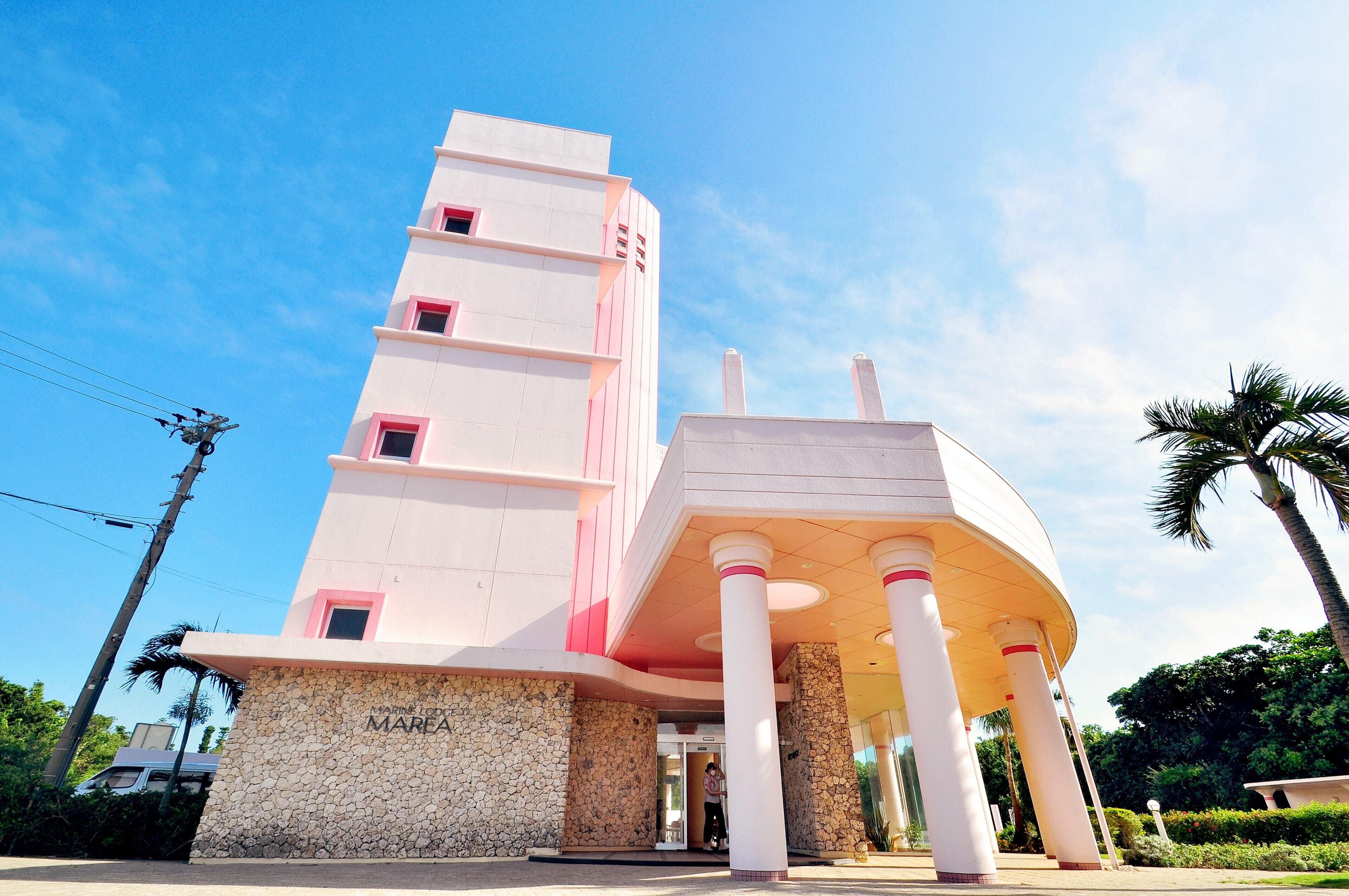 Un edificio de varios pisos con una entrada destacada y un porche sostenido por columnas.
