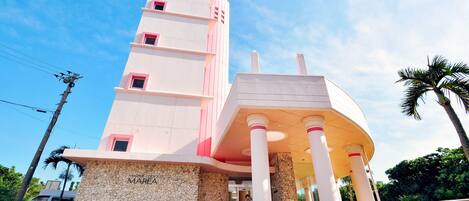 Un edificio de varios pisos con una entrada destacada y un porche sostenido por columnas.