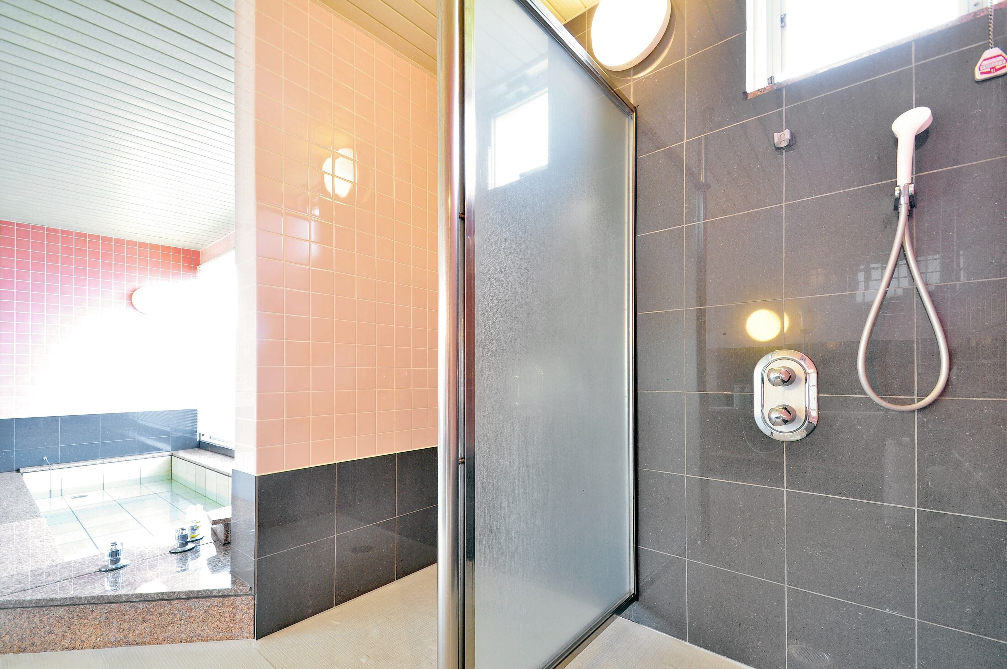 A modern bathroom with a glass shower enclosure, a handheld showerhead, and a wall-mounted faucet.