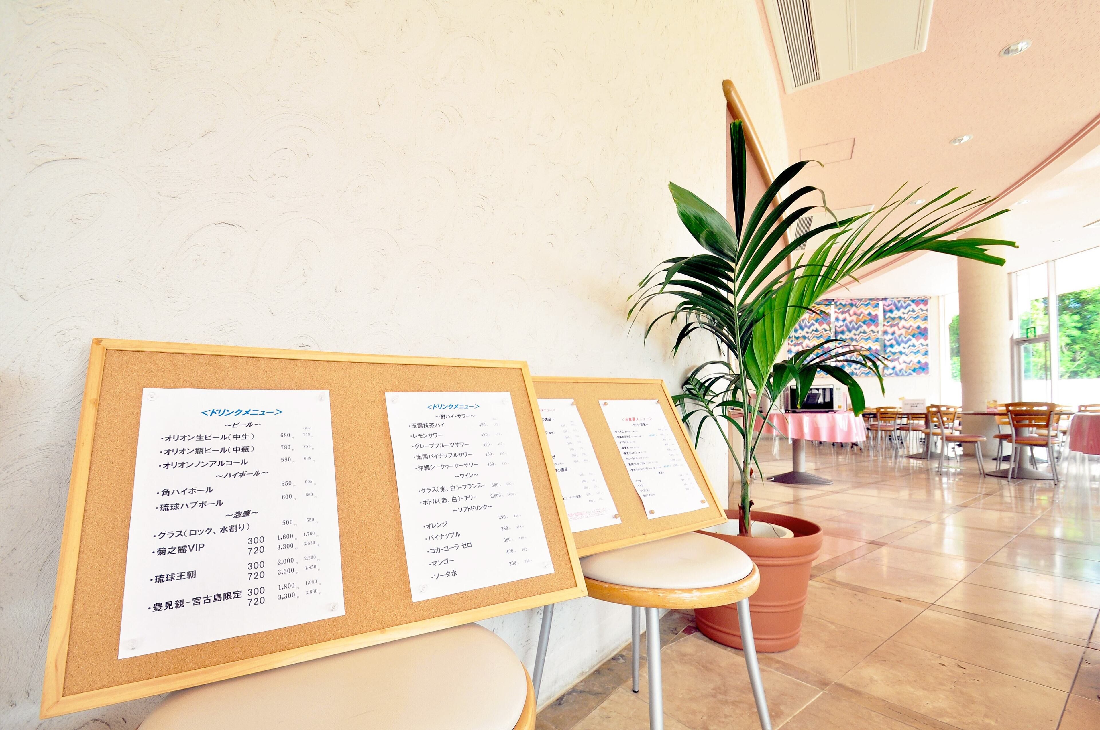 A menu board with food items and prices, a potted plant, and a seating area with tables and chairs.