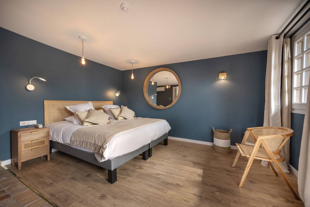 A bedroom with a bed, bedside tables, a mirror, and a chair.