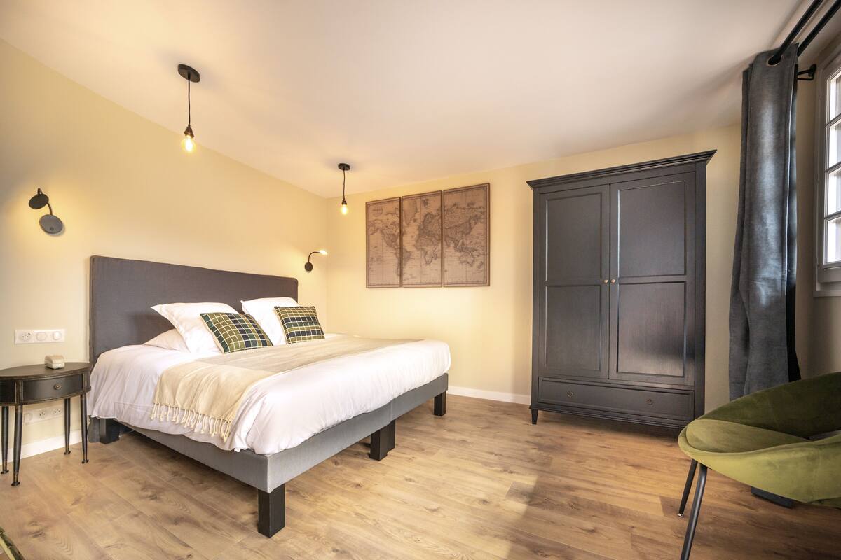 A bedroom with a bed, bedside tables, a wardrobe, and a chair.