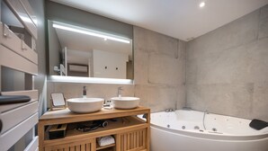 A modern bathroom with two sinks, a large bathtub, and a wooden vanity.