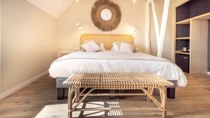 A bedroom with a large bed, bedside tables, a bedside lamp, a wall-mounted mirror, and a wooden bench.