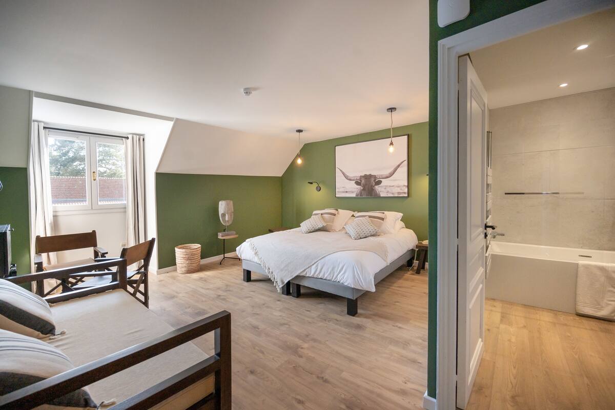 A bedroom with a bed, a desk, a chair, a window, and a bathroom.