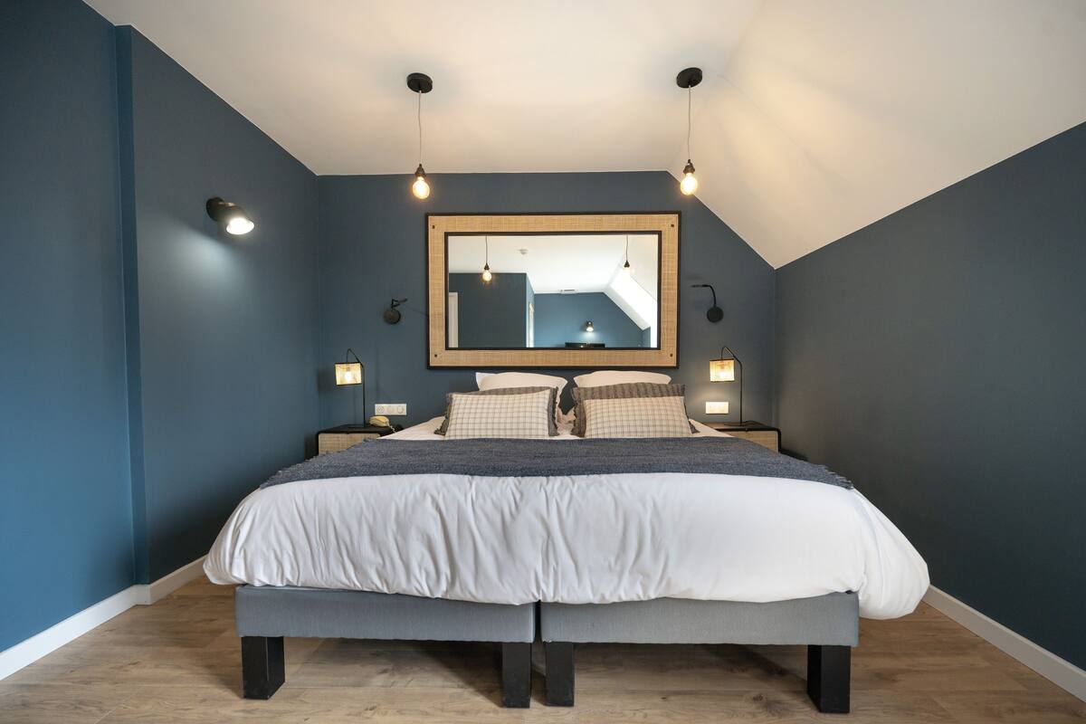 A bedroom with a large bed, a ceiling light fixture, and a mirror on the wall.