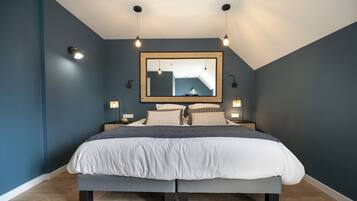 A bedroom with a large bed, a ceiling light fixture, and a mirror on the wall.