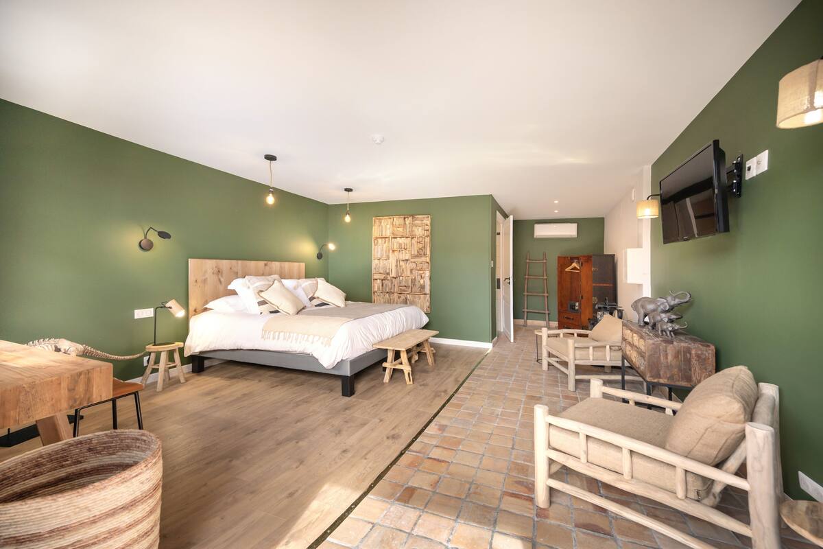 A bedroom with a bed, bedside table, lamp, and a wooden bench.
