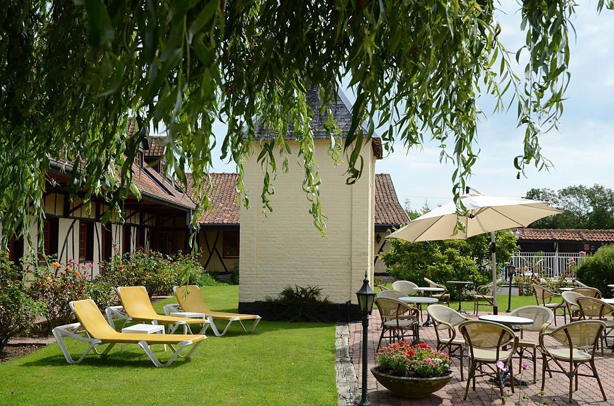 Un espace patio aménagé avec des sièges d’extérieur, comprenant des fauteuils et des tables de couleur jaune, protégés par des parasols.