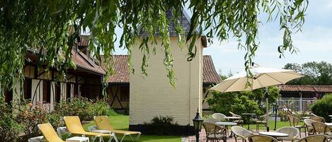 A patio area with outdoor seating, including yellow lounge chairs and tables with umbrellas.