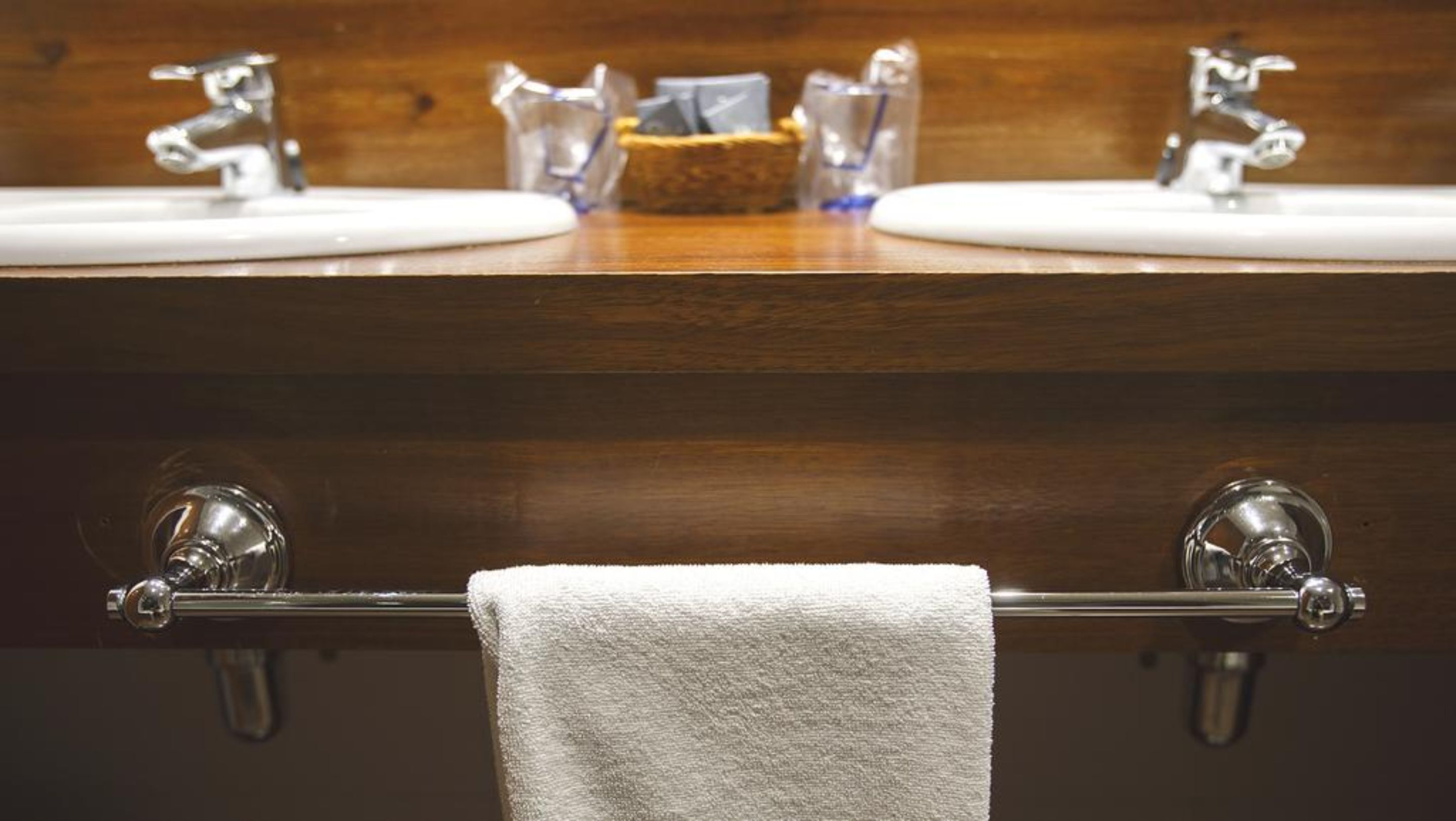 A bathroom with two sinks, a towel rack, and a soap dispenser.